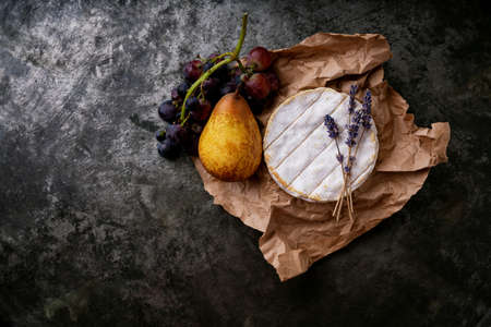 French cheese Camembert covered with honey, dried lavender stems on the paper  and freshly baked baguette over dark rustic background. Top view. Copy spaceの写真素材