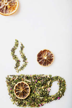 Dry herbal tea leaves spilled from the strainer and scattered in shape of cup with smoke  over white background. Creative concept. Top viewの写真素材