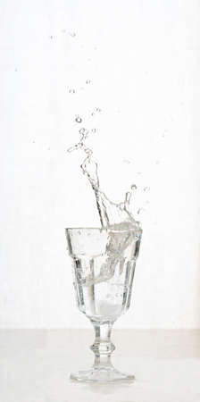 Vintage glass of sparkling water with splashes. Concept of liquid splashes and action in still lifeの写真素材