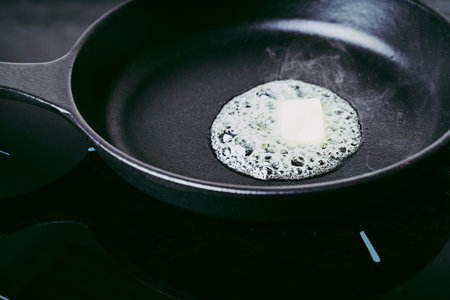 Cast Iron skillet  with melted butter on the stove. Cooking at home concept. Flat lay. Top Viewの写真素材