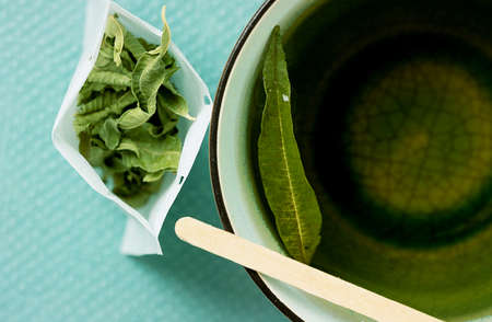 Lemon Verbena tea in a mug  with hand made teabag open over a tidewater green background. Top View. Flat Layの写真素材