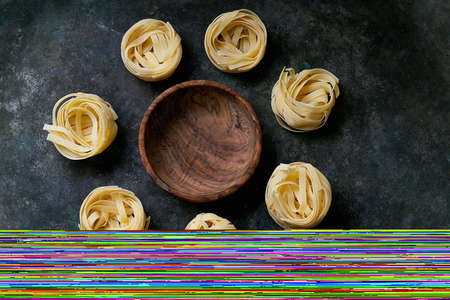 Traditional Italian Pasta Tagliatelle in a wooden bowl (olive tree) over a rustic background. Top...