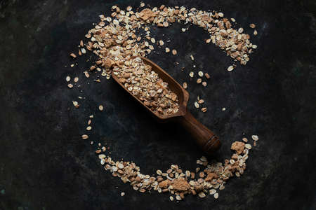 Granola, muesli in wooden olive tree scoop spread over a rustic metal background. Top View. Flat Layの写真素材