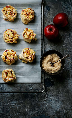 Home cooking concept. Preparation process of an apple swirls placed over a baking paper sheet ready to bake. decorated with apples and sugar. Top View Flat Lay.の写真素材