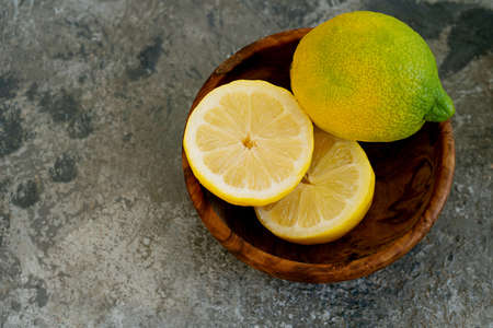 Lemons  in wooden olive tree bowl. cut in half. Top View. Flat Lay. Copy Spaceの写真素材