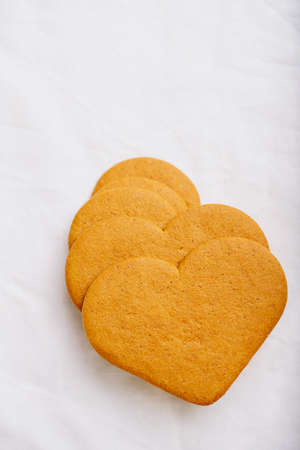 Heart shaped  gingerbread cookies  over a white textile background. Flat Lay. Top View