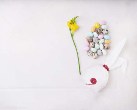 Chocolate Easter eggs glazed with pastel coloring and quail eggs over white background. Bunny shaped...