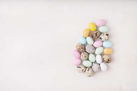 Chocolate Easter eggs glazed with pastel coloring and quail eggs over white background. Happy Easter concept. Copy space. Top viewの写真素材