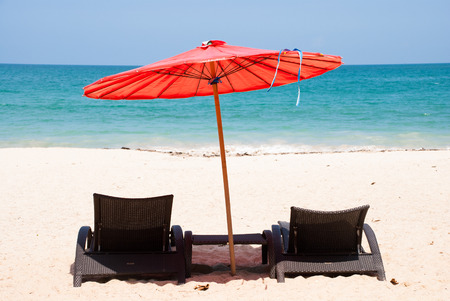 Sandy beach with red umbrella and beach chairの写真素材