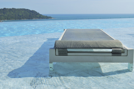 In summer vacation. Pool chairs on swimming pool seaview and blue sky.の写真素材
