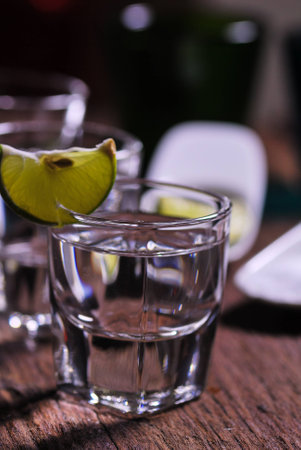 Glass of vodka shot with fresh lime on wooden tableの写真素材