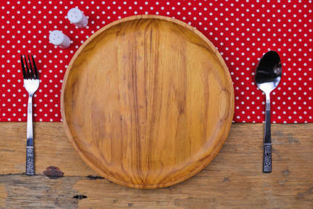 Wooden plate, tablecloth, spoon, fork on old table backgroundの写真素材