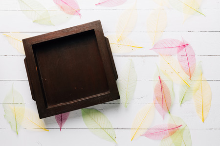 Frame made from wood with color dried leaves on wooden white background vintage retro filter