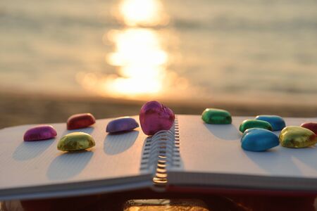 Chocolate heart shape  colorful laying on book at beach sunset