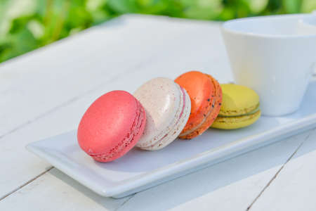 macaroon multicolored  with a cup of coffee on white table with sea and blue sky backgroundの写真素材