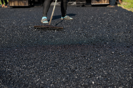 Worker operating asphalt paver machine during road construction and repairing works focus on asphalt roadの写真素材
