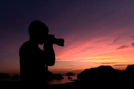 Photographer silhouette shooting seaand landscape  outdoors at sunset sunrise backgroundの写真素材
