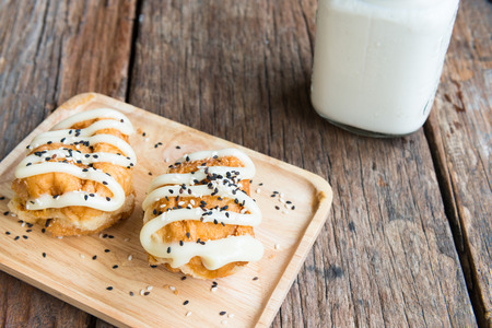 Buns with Sweetened Condensed Milk and Sesame black and white , with glass of milk on wooden backgroundの写真素材