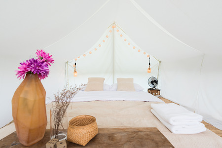 Inside a large white tent camp with bed and interior furnishingsの写真素材