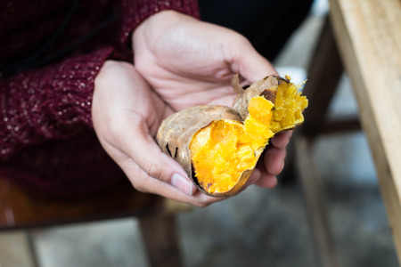 Girl hand hold roated sweet potatoの写真素材