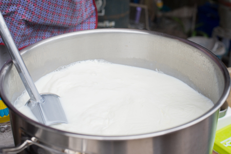 Hot milk boiled in metal pot, street foodの写真素材