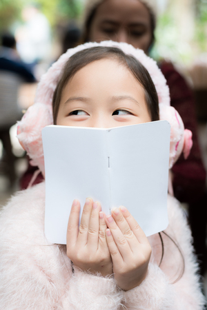 Kid sitting with book in front of her faceの写真素材