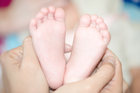 Mother hand hold baby toe close upの写真素材