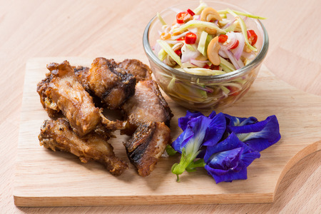 Fried fish with mango salad on wood backgroundの写真素材