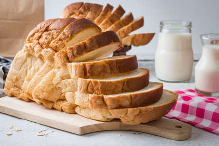 Fresh homemade  baked bread and sliced bread with milk on rustic white wooden tableの写真素材