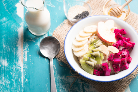 Hot and healthy food for Breakfast, Bowl of oatmeal porridge with bananas, apple, dragon fruit , kiwi and almonds. Top viewの写真素材