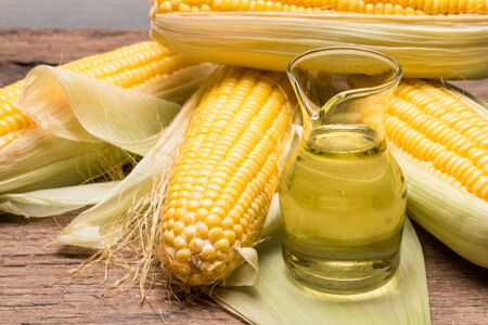 Corn oil and corn on rustic wooden background