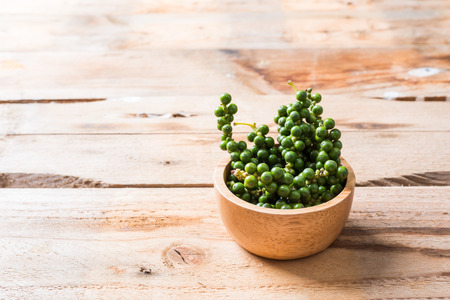 Fresh Peppercorns. Green pepper seeds,Bunches of fresh Black pepper on wood backgroundの写真素材