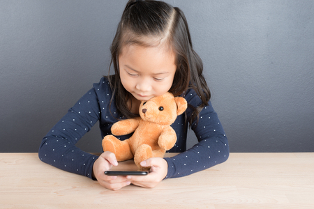 Portrait of asian little girl use smart phone with smile and funの写真素材