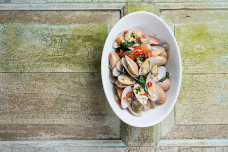 Short neck clams stir fried with sauce basil and chili spicy sauce on rustic wooden backgroundの写真素材