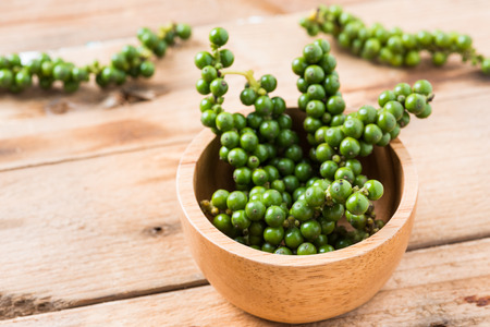 Fresh Peppercorns. Green pepper seeds,Bunches of fresh Black pepper on wood backgroundの写真素材