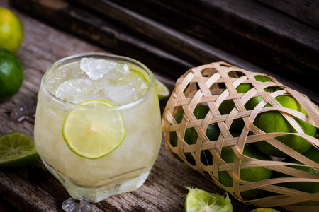 Cocktail with ice and lime slice  on old wooden tableの写真素材