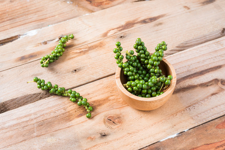Fresh Peppercorns. Green pepper seeds,Bunches of fresh Black pepper on wood backgroundの写真素材