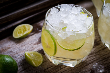 Cocktail with ice and lime slice  on old wooden tableの写真素材