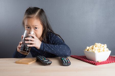 Portrait of asian little girl age 6 years drink cola soda in glassの写真素材