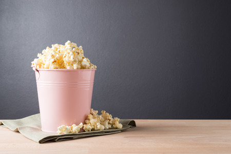 Popcorn in pink can  on wooden backgroundの写真素材