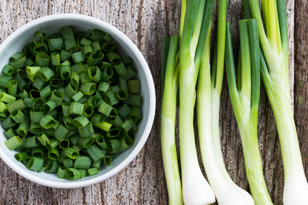Chopped spring onions in white bowl on wooden tableの写真素材