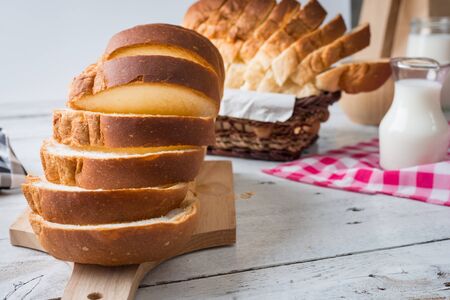 Fresh homemade  baked bread and sliced bread with milk on rustic white wooden table