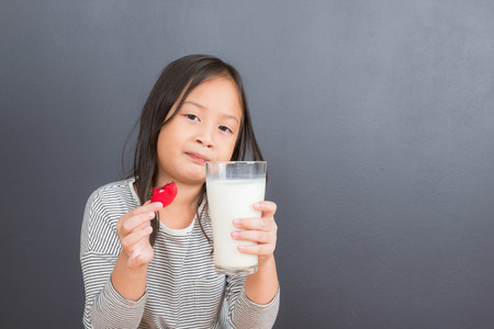 Cute little asian girl age 6 years eating sweet macarons and drink milkの写真素材