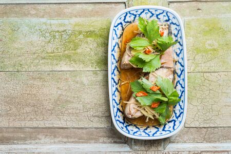 Steamed snapper fish with soy sauce Celery and ginger in plate on rustic wooden bcakgroundの写真素材