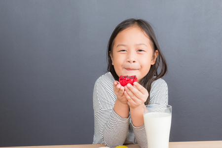 Cute little asian girl age 6 years eating sweet macaronsの写真素材