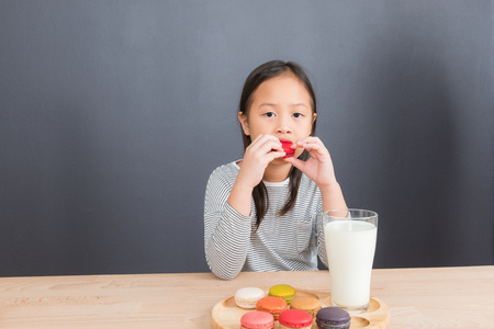 Cute little asian girl age 6 years eating sweet macaronsの写真素材