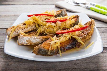 Deep fried fish with ginger and soy sauce on wooden tableの写真素材