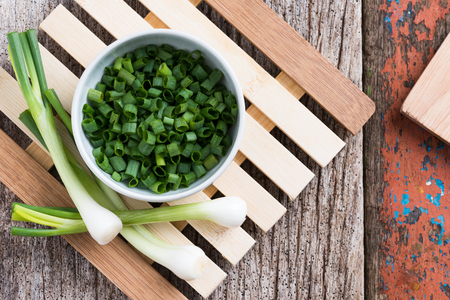 Chopped spring onions in white bowl on wooden tableの写真素材