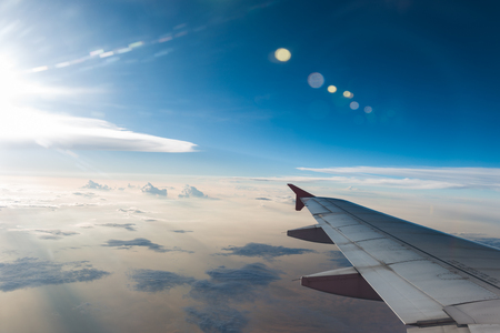 The plane is flying through the sunset sky and wing of aircraft can be seen from the airplaneの写真素材