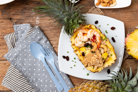 Pineapple fried rice with seafood served in a pineapple on the wooden tableの写真素材
